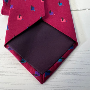 Red patterned tie with a dark pocket square on a light wooden surface