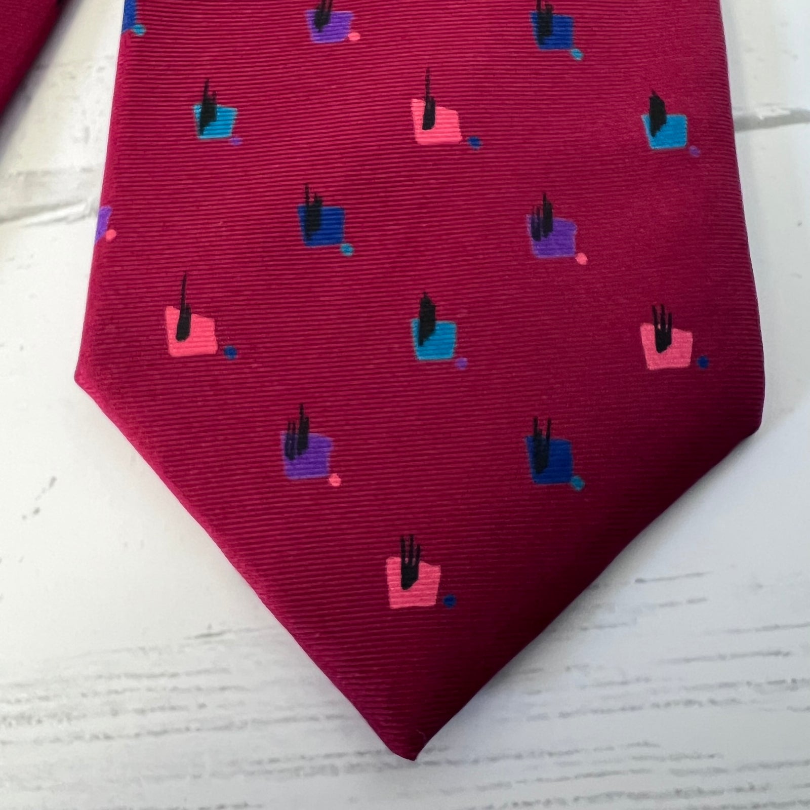 Maroon tie with geometric pattern on a light wooden surface