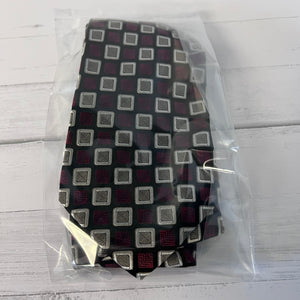Patterned tie in a clear plastic bag on a light wooden surface