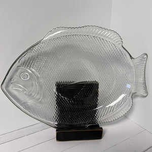 Clear glass fish-shaped platter on a white surface