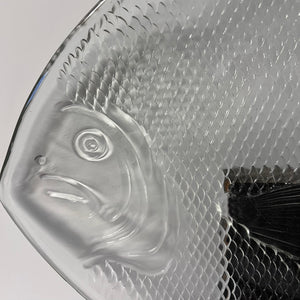Clear glass fish-shaped object with textured surface on a white background
