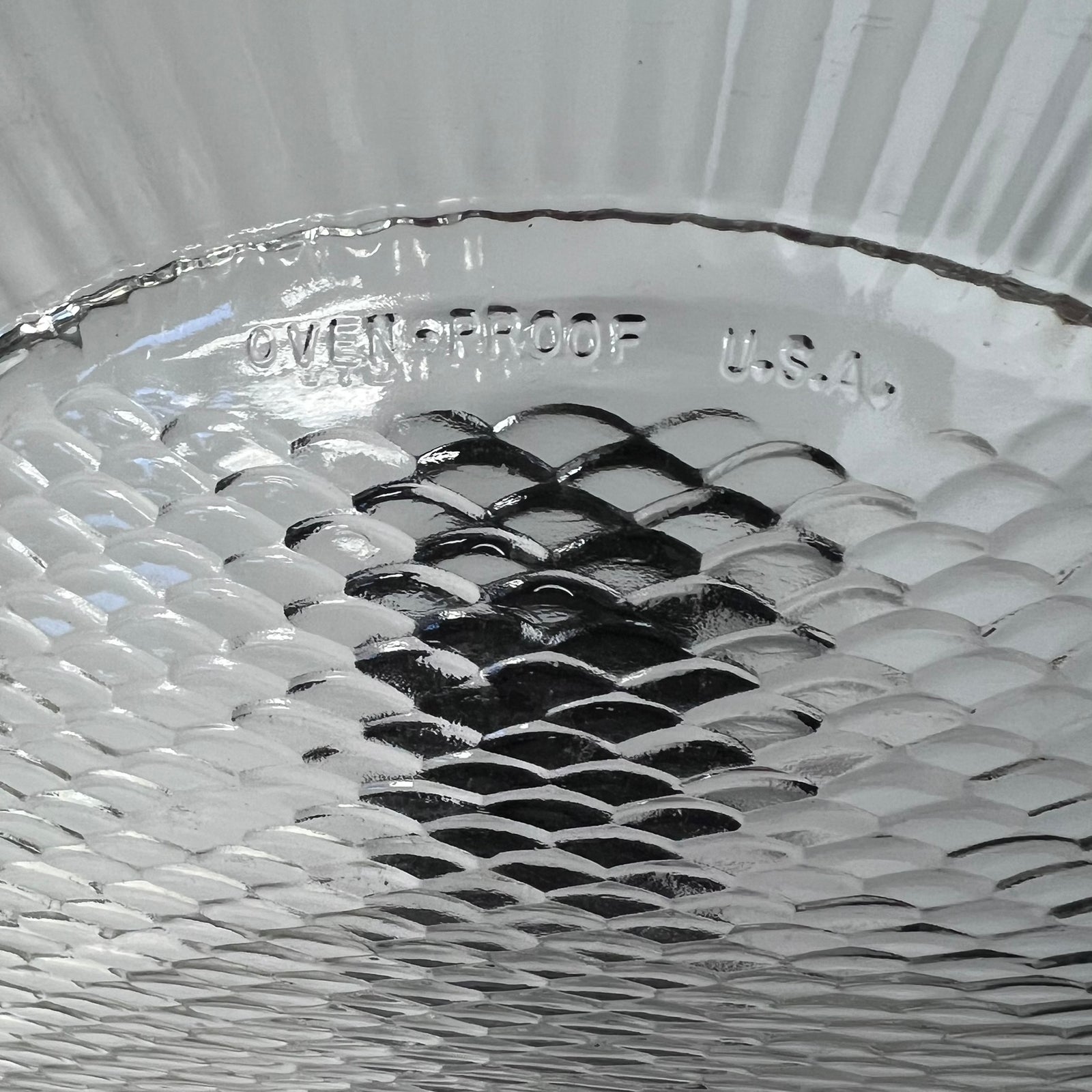 Close-up of a glass dish with 'Oven Proof U.S.A.' text on a textured background