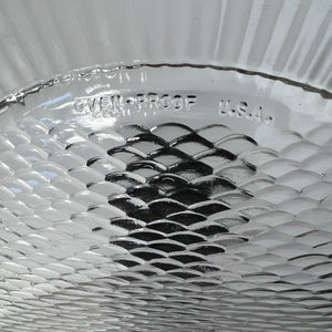 Close-up of a glass dish with 'Oven Proof U.S.A.' text on a textured background