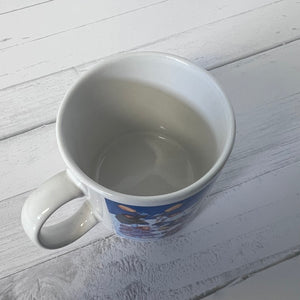 White mug with a blue design on a light wooden surface