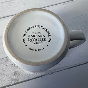 Ceramic mug with 'Arctic Circle Enterprises, Inc.' branding on a light wooden surface