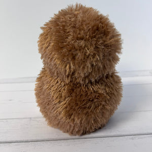 Brown fluffy object on a light wooden surface