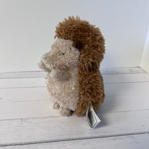 Plush hedgehog toy on a white wooden surface