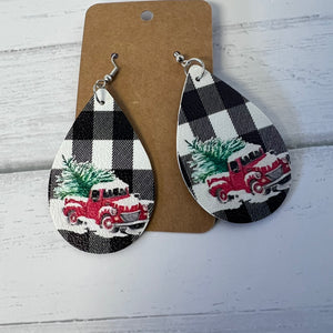Teardrop-shaped earrings with black and white plaid design featuring a red truck and Christmas tree on a brown card.