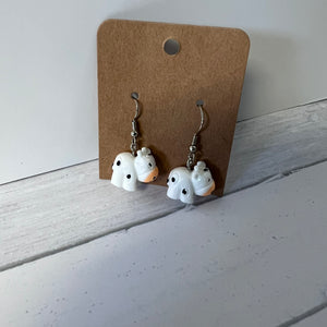 Pair of ghost-shaped earrings on a brown card against a white background
