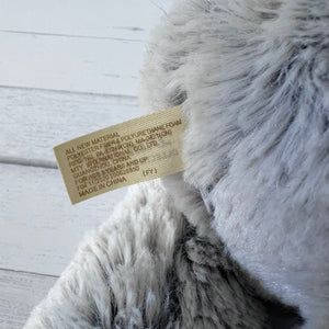 Close-up of a fluffy gray pillow with a label on a light wooden surface