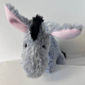 Plush donkey toy on a white surface with a plain background