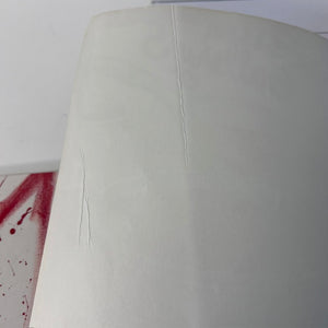 Close-up of a white chair with red liquid stain on a white background