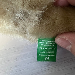 Close-up of a green label on a plush toy with a hand holding it.