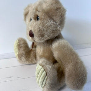 Beige teddy bear on a white wooden floor
