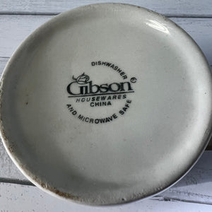 Gibson Housewares China plate with branding on a wooden surface