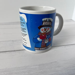 Blue mug with Hershey's snowman design on a white wooden surface