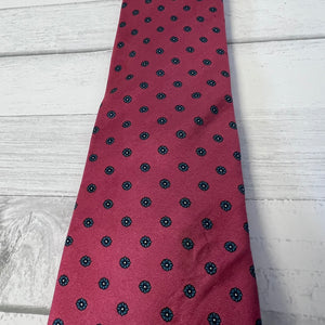 Red tie with black floral pattern on a light wooden surface