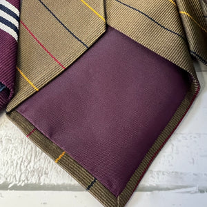Purple fabric pocket square with plaid border on a textured surface