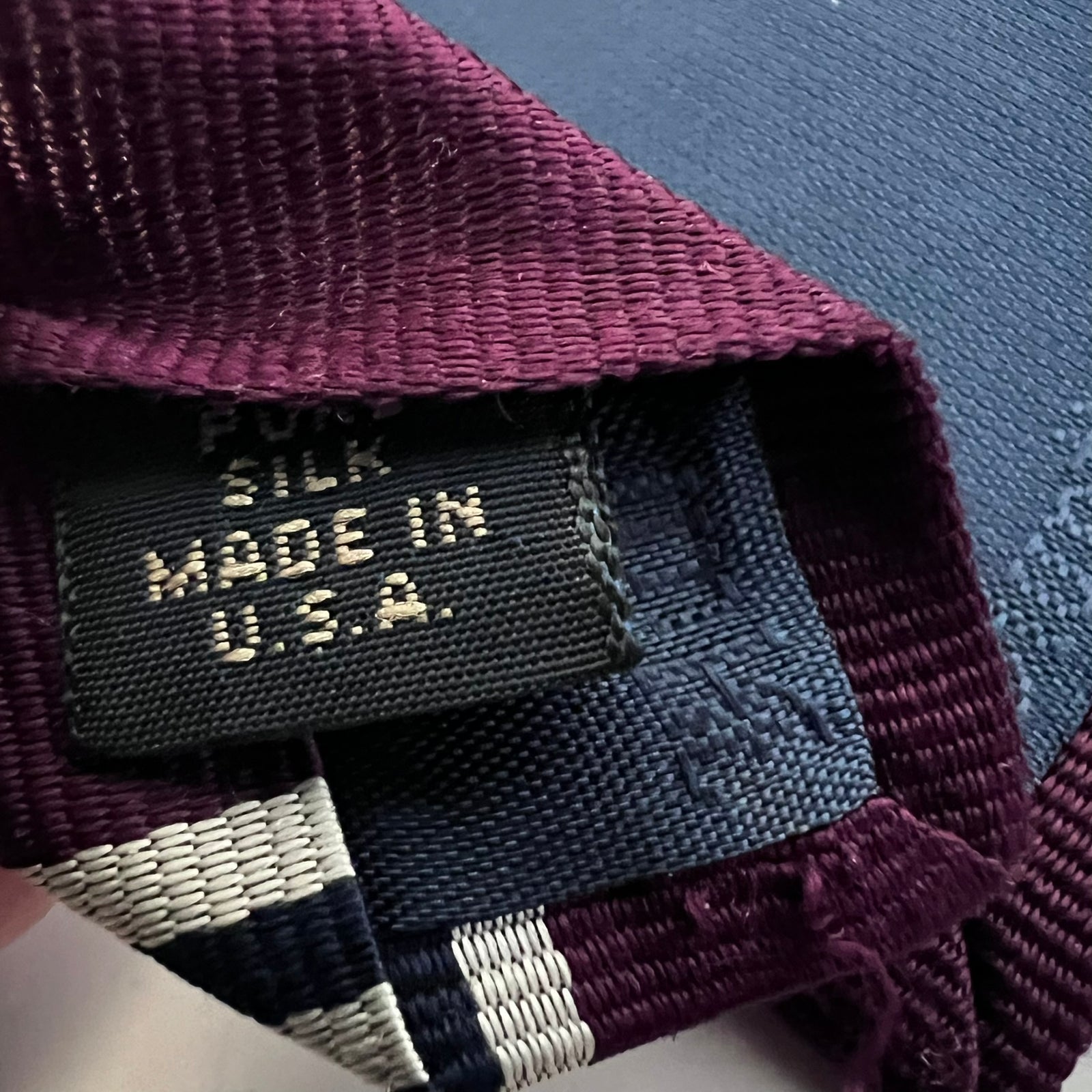 Close-up of a silk tie with 'Made in U.S.A.' label on a textured surface.