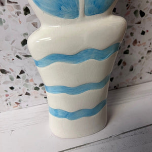 Ceramic vase with blue wave patterns on a white surface