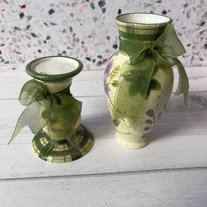 Two ceramics with green ribbons on a white surface with a patterned wall background.