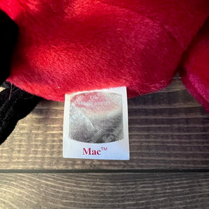 Red plush toy with a 'Mac' label on a wooden surface