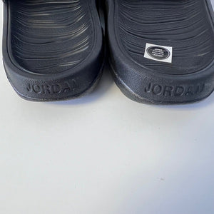 Black Jordan sandals on a white background