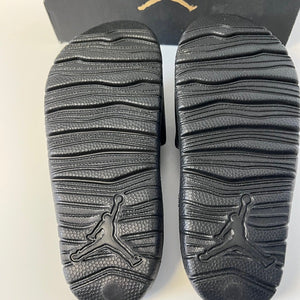 Black Jordan slides showing sole pattern with logo on a white background