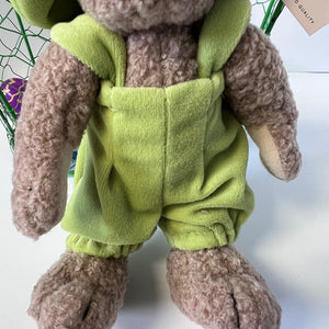 Plush toy rabbit wearing green overalls on a white background
