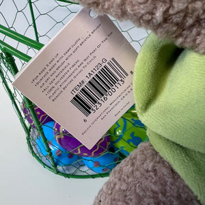 Close-up of a toy with a label and barcode, featuring a green basket in the background.