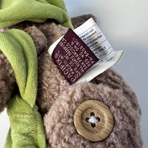 Close-up of a textured fabric item with a button and a label on a light gray background
