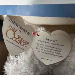 Close-up of a plush toy with a 'The Golden Compass' tag and information card.