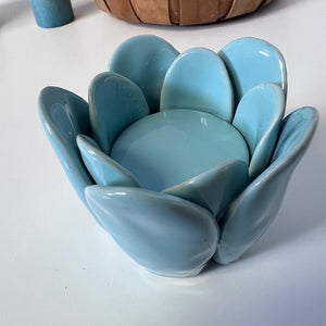 Blue ceramic flower-shaped candle holder on a white surface