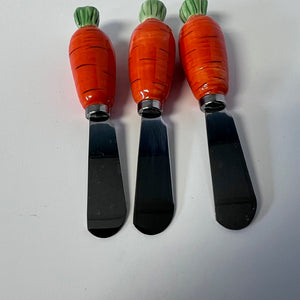 Three carrot-shaped spreaders with stainless steel blades on a white background