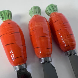 Three carrot-shaped knives with green tops on a white background