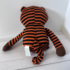 Striped tiger plush toy on a white wooden floor with a visible tag.