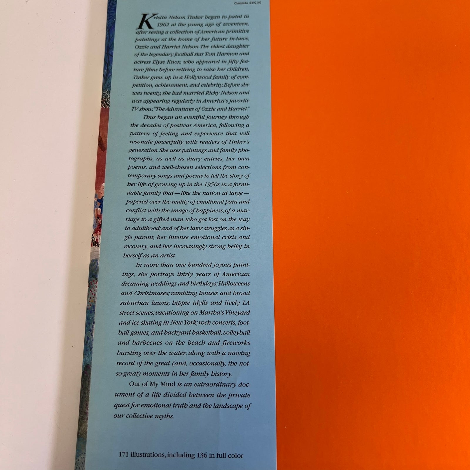 A printed book or booklet page with a large black text column on a white background, photographed against a blue-and-white striped surface with a warm orange glow on the right side.