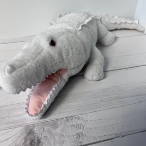 Gray plush alligator toy on a light wooden floor