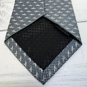 Black textured square on a gray and white patterned fabric background