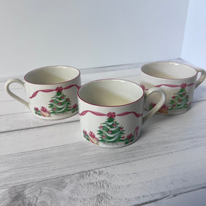 Three ceramic mugs with Christmas tree design on a white wooden surface
