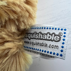 Close-up of a 'squishable' label on a plush toy with a white background
