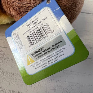 Back of a plush toy with a warning label on a gray surface