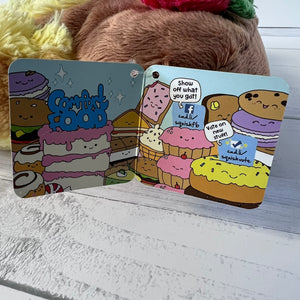 Two colorful card designs with cartoon food characters on a wooden surface.