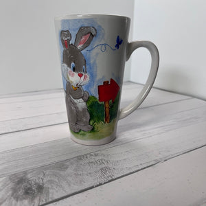 White mug with a painted rabbit design on a wooden surface