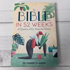 Book titled 'The Bible in 52 Weeks' on a wooden surface