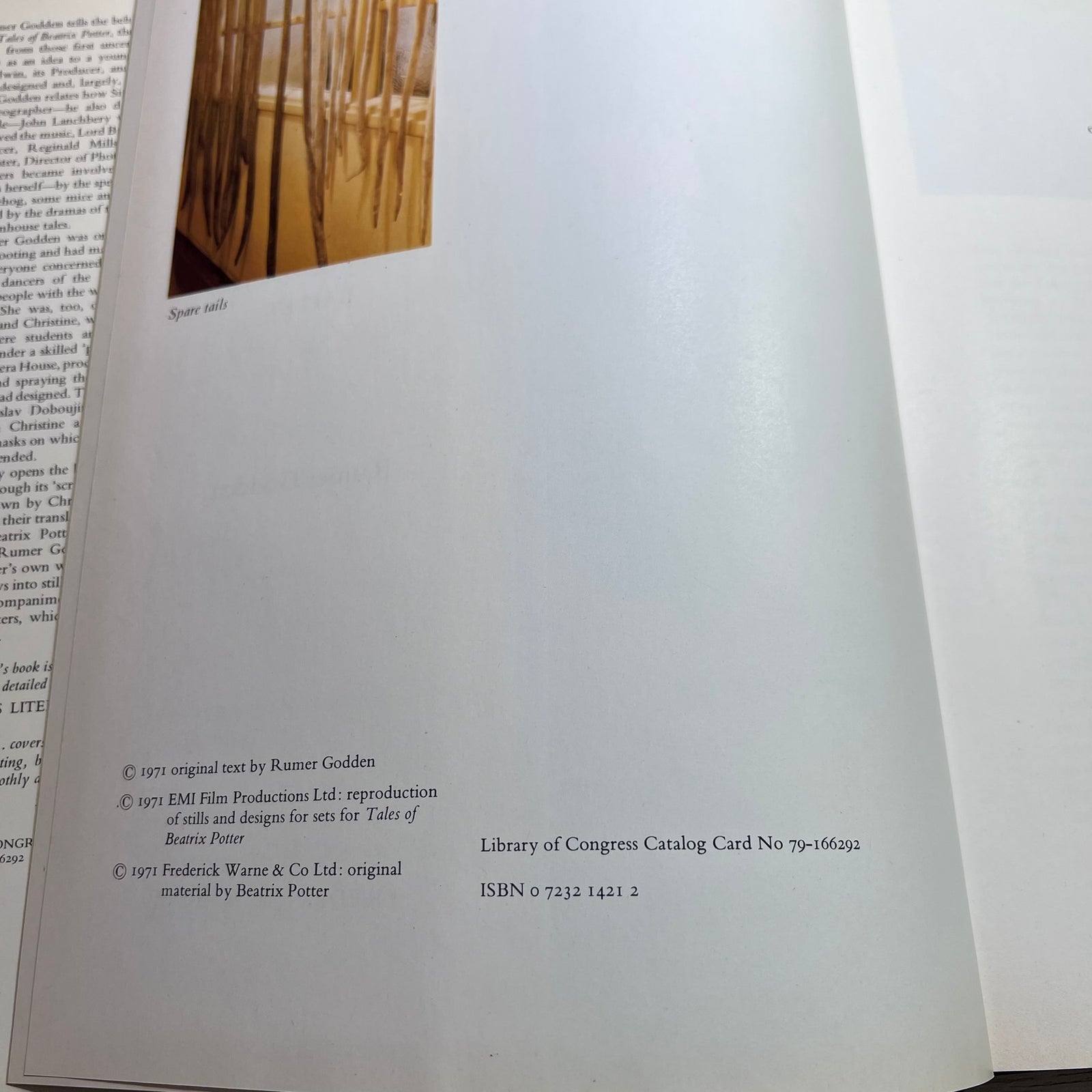 A close-up of an open book or booklet page showing a small inset photograph of a curtain scene and printed text credits, including 'Rumer Golden' and 'Frederick Wayne & Co Ltd'.