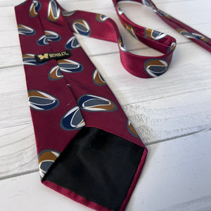 Maroon tie with geometric pattern on a white wooden surface