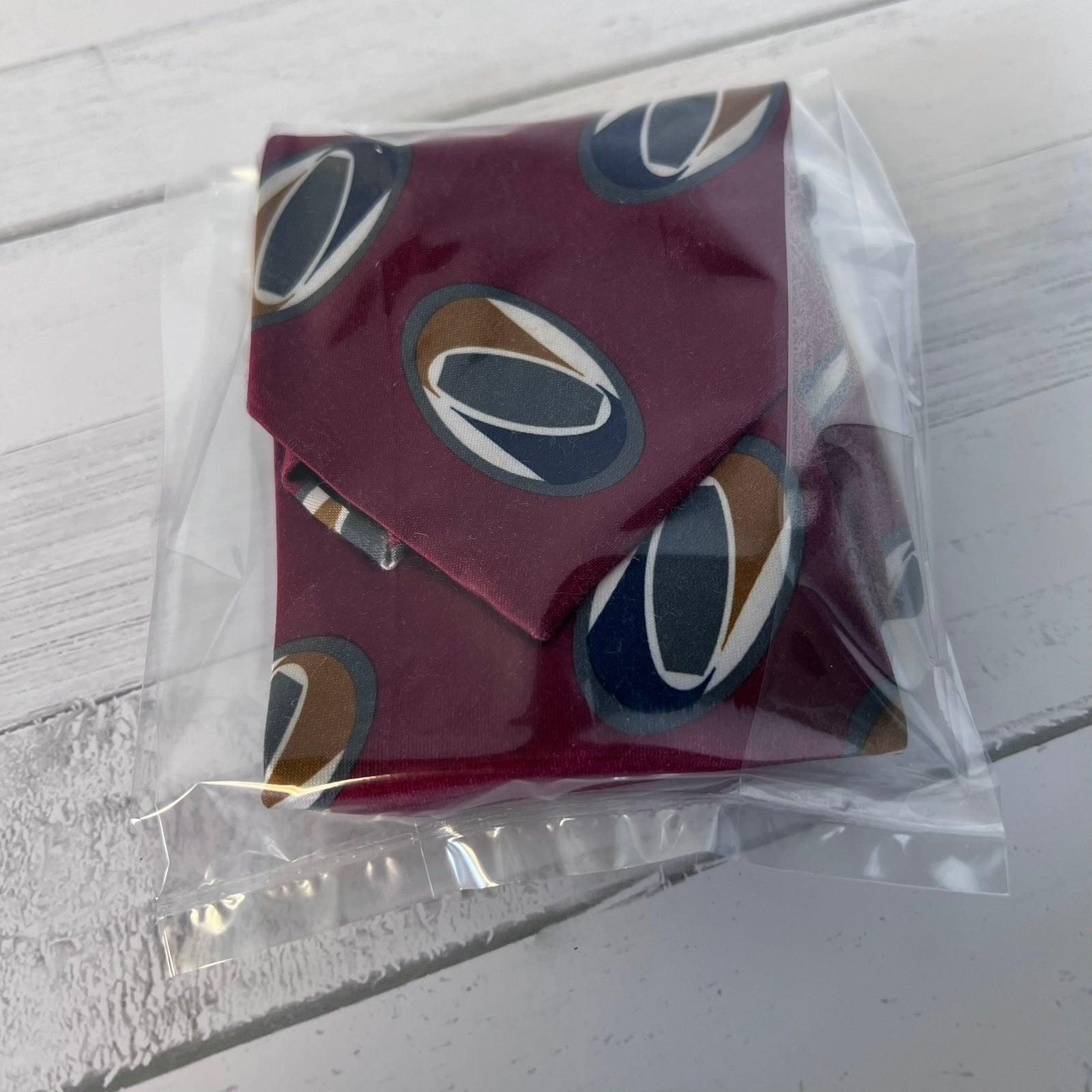 Red fabric with circular patterns in clear packaging on a white wooden surface