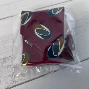 Red fabric with circular patterns in clear packaging on a white wooden surface