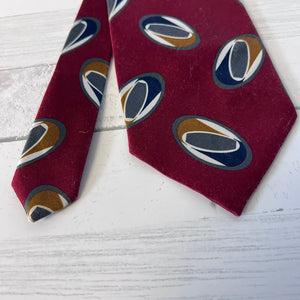 Maroon tie with circular pattern on a light wooden surface